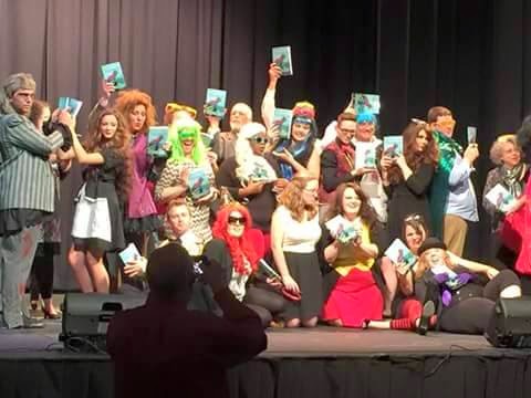 Actors from Tift Theatre for the Performing Arts holds up DOGWOOD BLUES by Brenda Sutton Rose.